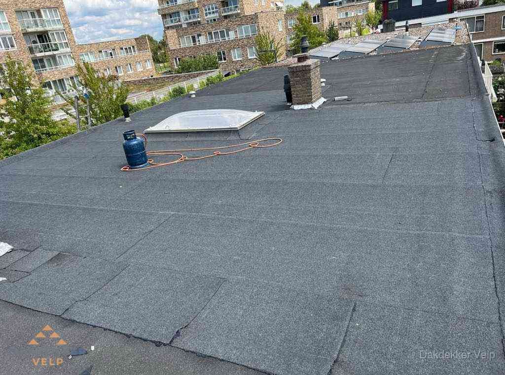 Bitumen dakbedekking op plat dak met lichtkoepel en schoorsteen in Velp