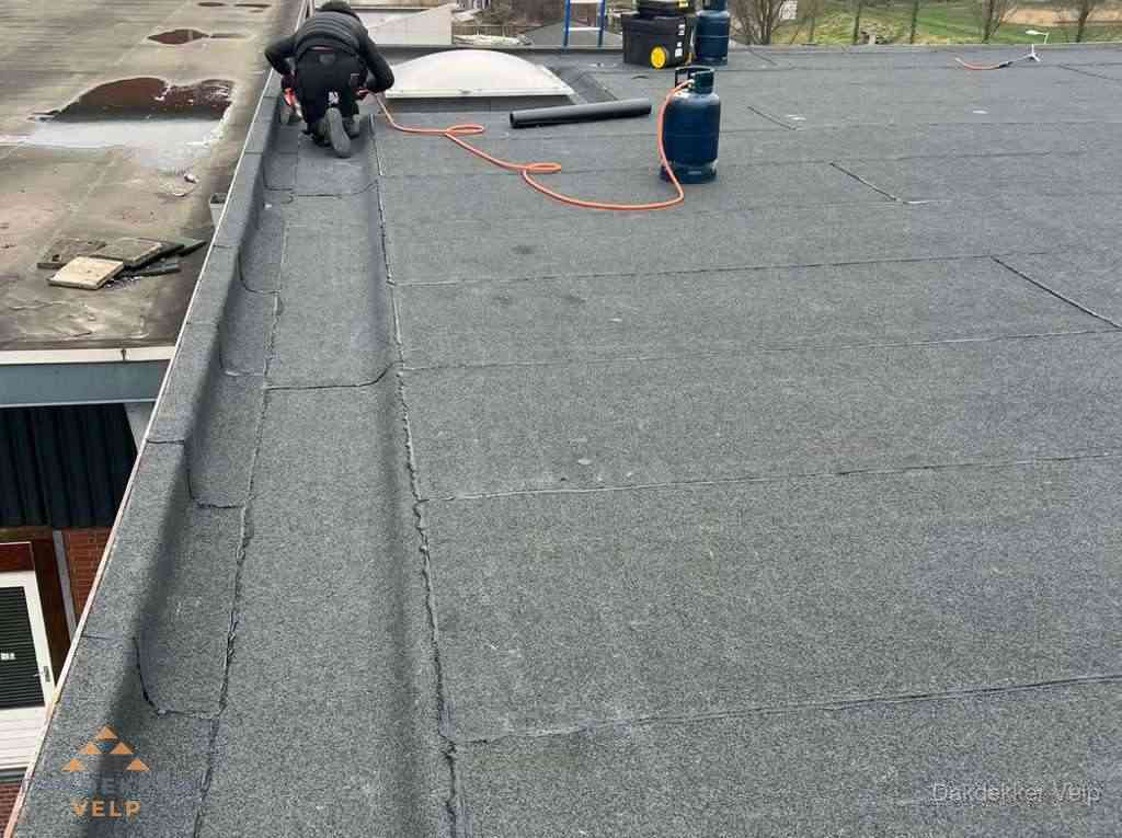 Dakdekker repareert bitumen dakbedekking op groot plat dak in Velp